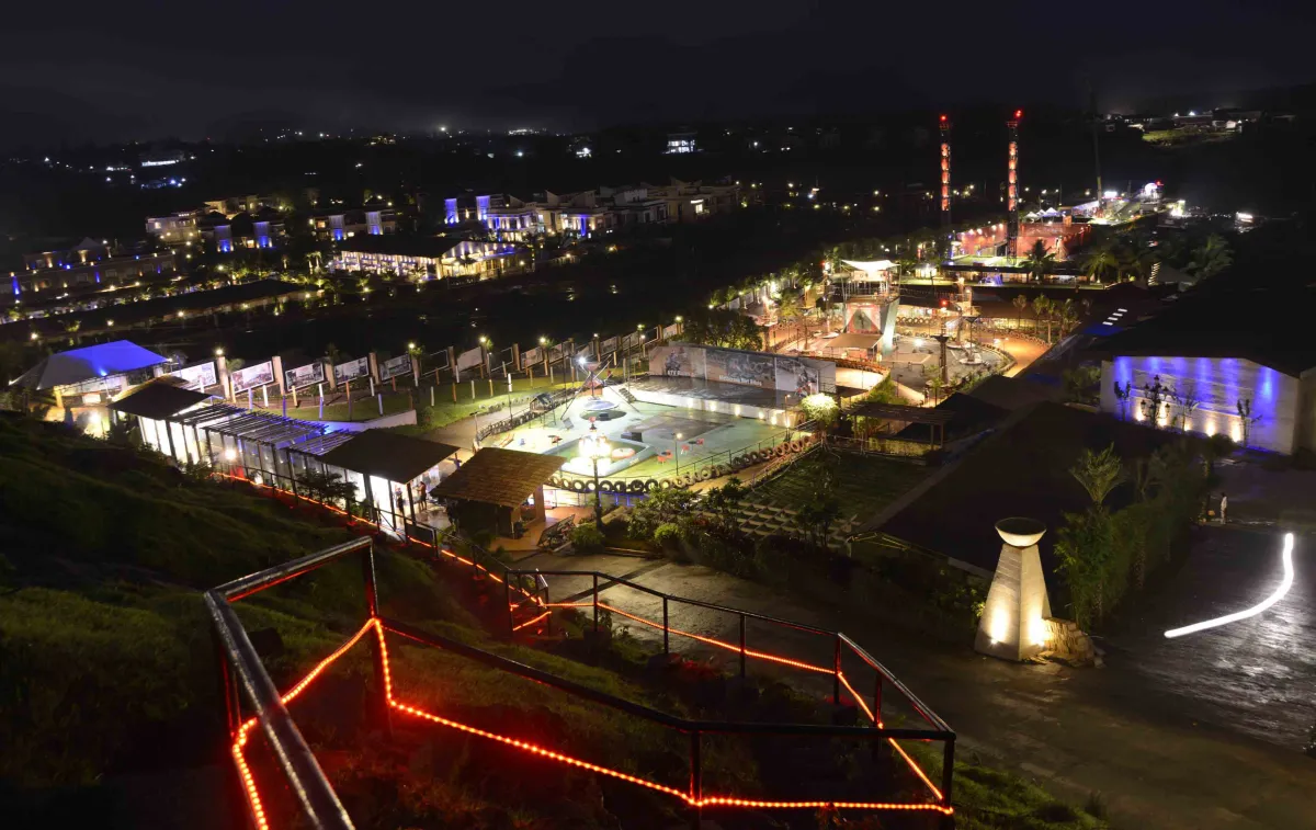 Della Adventure lit up at night: the motocross arena, activity zones and towers, with Della Resorts beyond, Lonavala