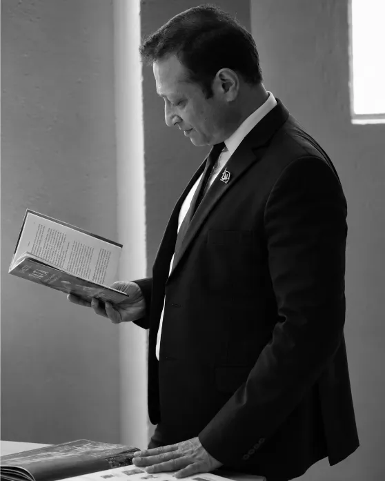 Jimmy Mistry reading a design book beside a window, black-and-white portrait